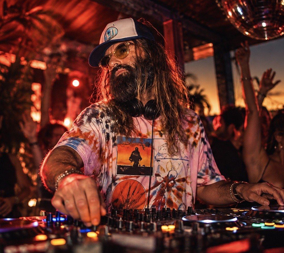 DJ Bones performing behind the decks in a lively red-lit room