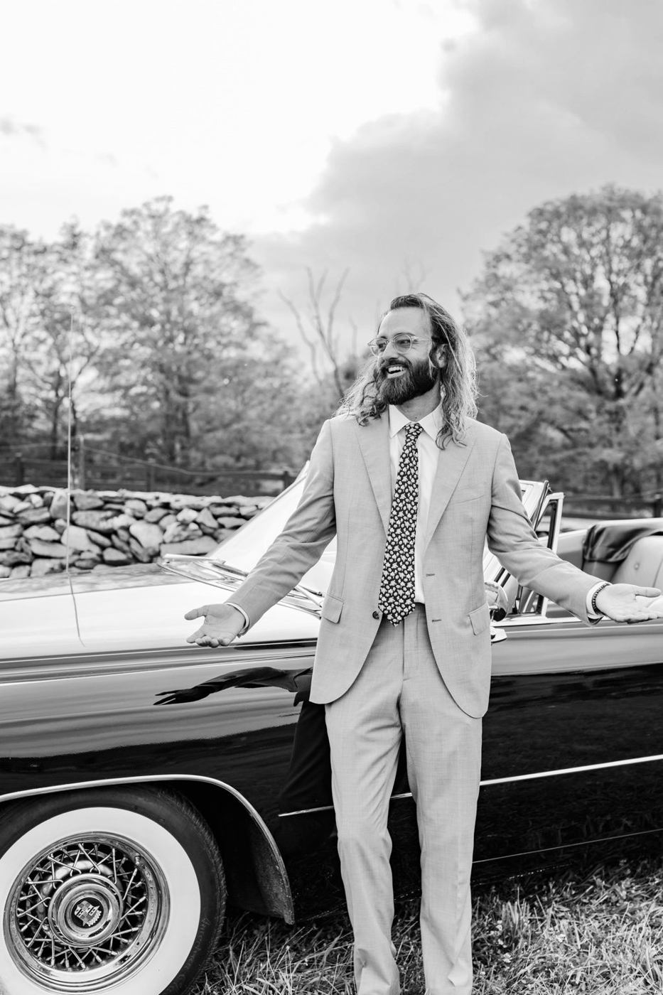 DJ Bones in a suit beside a vintage car